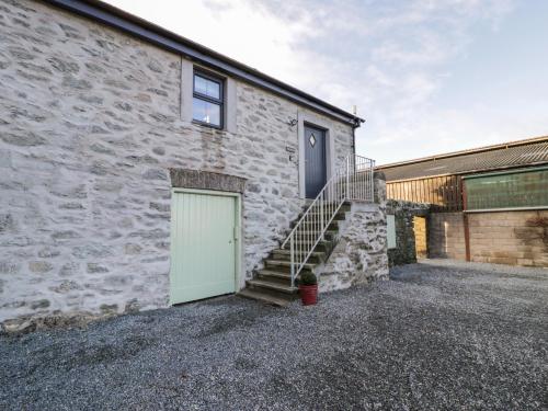 a stone house with a green door and stairs at The Granary in Holyhead