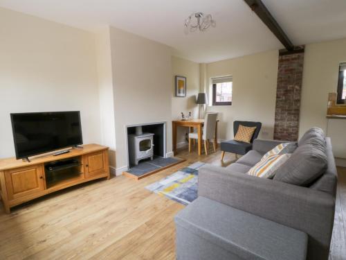 a living room with a couch and a flat screen tv at The Stable in York