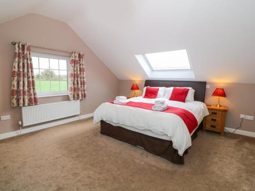 una camera da letto con un letto con cuscini rossi e una finestra di Stabl a Llangybi