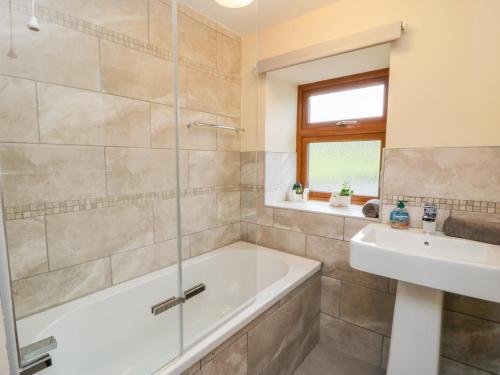 ein Badezimmer mit einer Badewanne und einem Waschbecken in der Unterkunft Acorn Cottage in Bradford