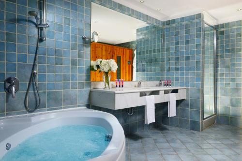 a blue tiled bathroom with a tub and a sink at UNA HOTELS Capotaormina in Taormina