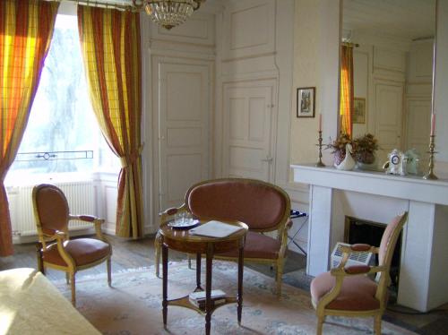a living room with chairs and a table and a fireplace at Le Chateau de Prauthoy in Prauthoy