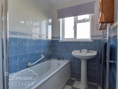 a bathroom with a bath tub and a sink at Hillview Bungalow in Burton Bradstock