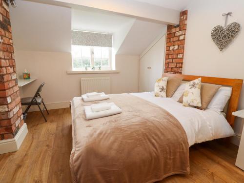 a bedroom with a large bed with two towels on it at Commonwood Cottage in Wrexham