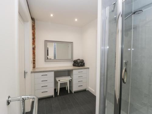 a bathroom with a vanity with a mirror and a shower at The Stable in York