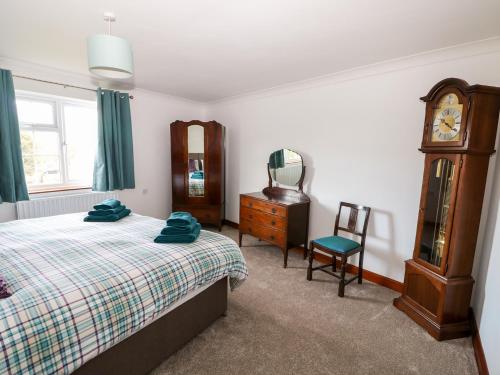 1 dormitorio con cama, reloj y silla en Balmedie, en Market Rasen