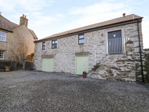 a stone house with green garage doors on a gravel driveway at The Granary in Holyhead