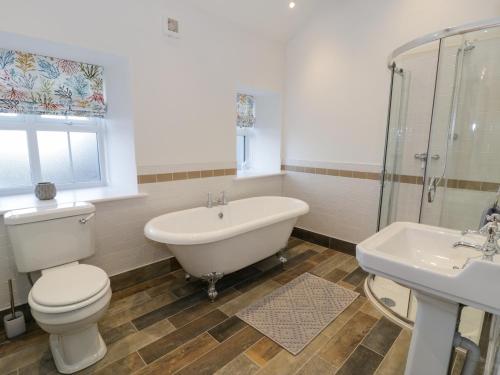 a bathroom with a tub and a toilet and a sink at The Granary in Holyhead