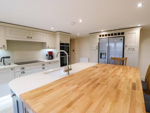 a kitchen with white cabinets and a wooden counter top at Town Farm in Darlington