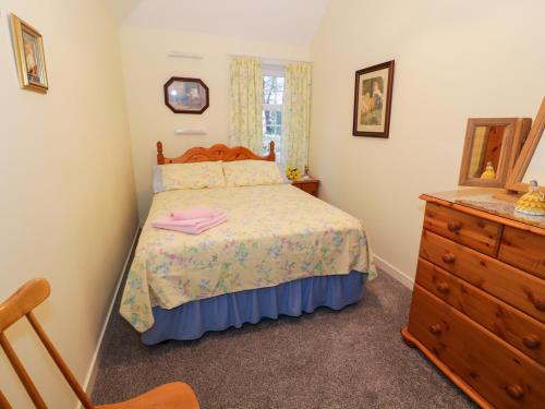a small bedroom with a bed and a dresser at Garden Cottage in Castle Douglas