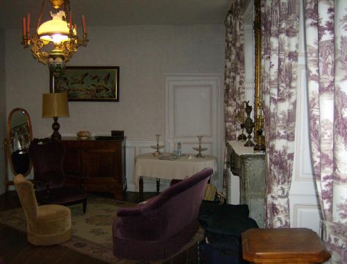 a living room with a purple chair and a table at Le Chateau de Prauthoy in Prauthoy