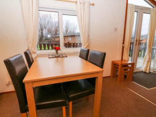a dining room table with black chairs and a window at The Cedars in Carnforth