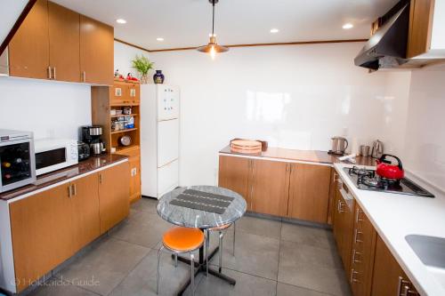a kitchen with wooden cabinets and a table in it at RUSUTSU HOLIDAY CHALET in Rusutsu