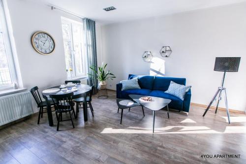 uma sala de estar com um sofá azul e uma mesa em 4YOU APARTMENT em Toruń