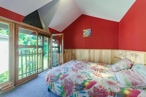 um quarto com paredes vermelhas, uma cama e uma varanda em L'Élassier em Saint-Priest-sous-Aixe