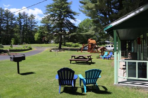 two blue chairs sitting in the grass next to a grill at Rowe's Adirondack Cabins of Schroon Lake in Schroon Lake