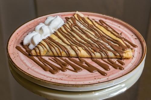 a dessert on a pink plate with chocolate icing at Motel Felikitas in Laktaši