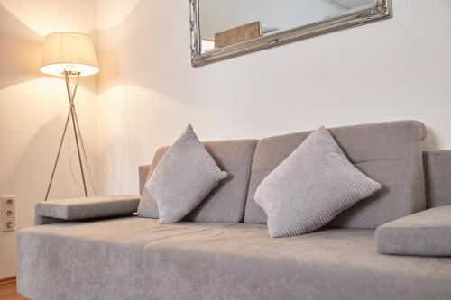 ein graues Sofa mit zwei Kissen im Wohnzimmer in der Unterkunft Modern Apartment suitable for Longstays in Wien