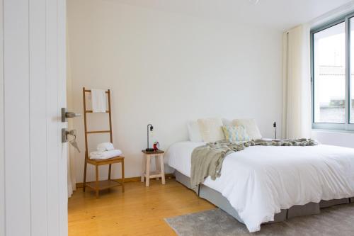 a white bedroom with a bed and a window at Casa dos Caldeiras in Lajes do Pico