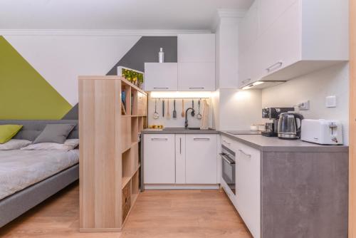 eine Küche mit weißen Schränken und ein Bett in einem Zimmer in der Unterkunft The Spot - fully equipped, central, modern studio by Flat Mаnager in Sofia