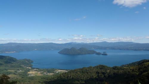a view of a lake with trees and mountains at RUSUTSU HOLIDAY CHALET in Rusutsu