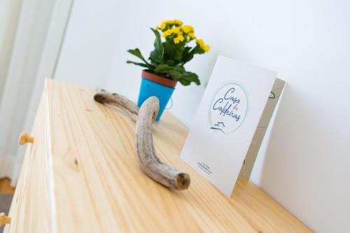 a wooden table with a vase with flowers and a knife at Casa dos Caldeiras in Lajes do Pico