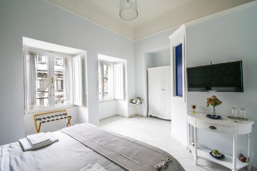 a white bedroom with a bed and a tv at Domus Sibyllina, Galleria Umberto I in Naples