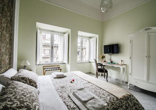 a bedroom with a bed and a desk and two windows at Domus Sibyllina, Galleria Umberto I in Naples