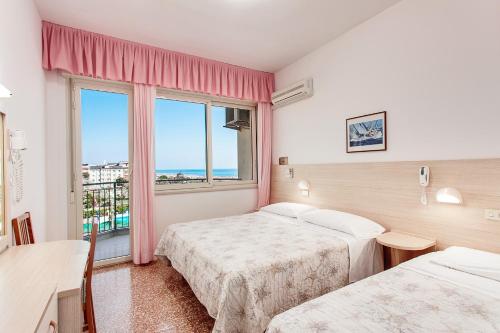 una camera d'albergo con due letti e una finestra di Hotel Silver a Milano Marittima