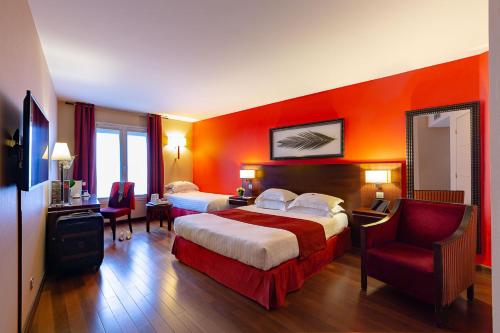 a hotel room with two beds and a chair at Hotel de Berny in Antony