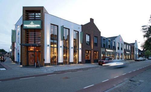 un coche conduciendo por una calle de la ciudad con edificios en GuestHouse Hotel Kaatsheuvel-Waalwijk, en Kaatsheuvel
