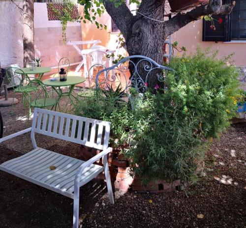 a white bench sitting in front of a tree at Sweet Home & Apartments in Fontane Bianche