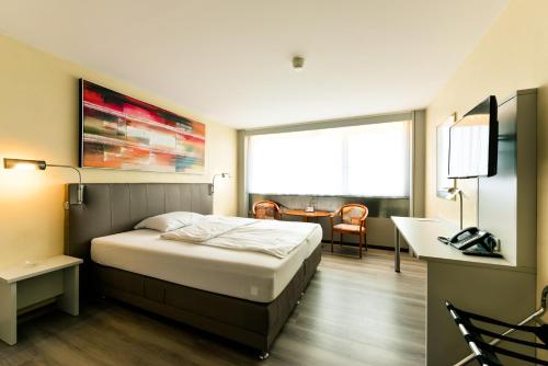een hotelkamer met een bed, een bureau en een raam bij City Hotel Heilbronn in Heilbronn