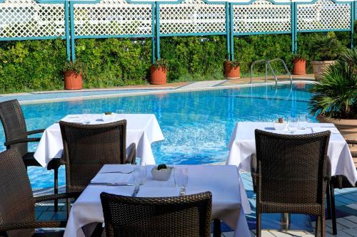 a restaurant with two tables and a swimming pool at Park Hotel Brasilia in Lido di Jesolo