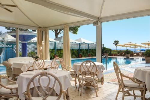 un restaurante con mesas y sillas blancas y una piscina en Park Hotel Brasilia, en Lido di Jesolo