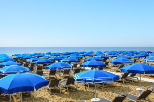 a group of blue umbrellas and chairs on the beach at Park Hotel Brasilia in Lido di Jesolo