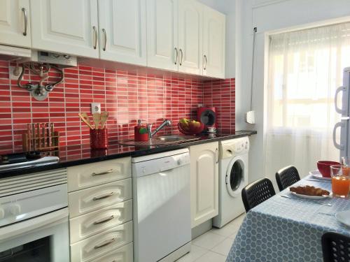 a kitchen with white cabinets and red tiles at Simply@Home in Setúbal