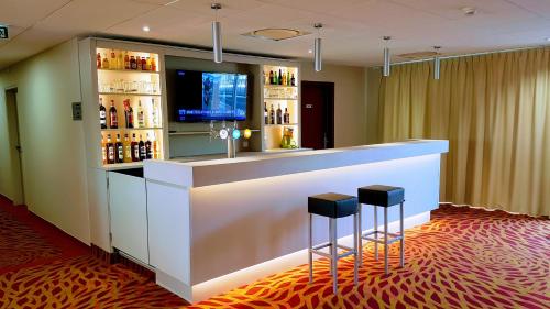 a bar in a hotel with two stools at The Originals City, Hôtel Acadine, Pont-Audemer in Pont-Audemer