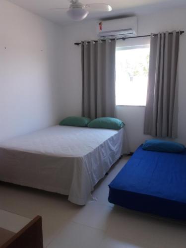 Un dormitorio con dos camas y una ventana. en Casa Recanto de Guarajuba, en Guarajuba
