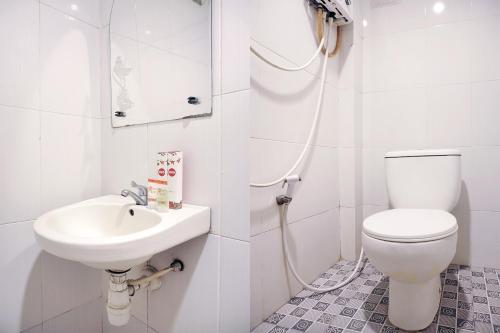 a white bathroom with a toilet and a sink at SUPER OYO 409 Pondok Helomi in Yogyakarta