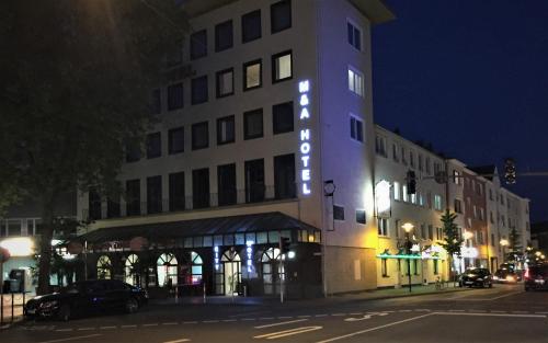 un grand bâtiment avec un panneau éclairé dans l'établissement M&A Cityhotel Hildesheim, à Hildesheim