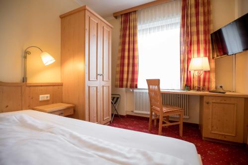 a hotel room with a bed and a desk and a window at Wirtshaus Restaurant Pension Steirerland in Mureck