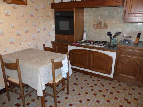 a kitchen with a table and a stove at Chez Karinette in Les Rivières-Henruel