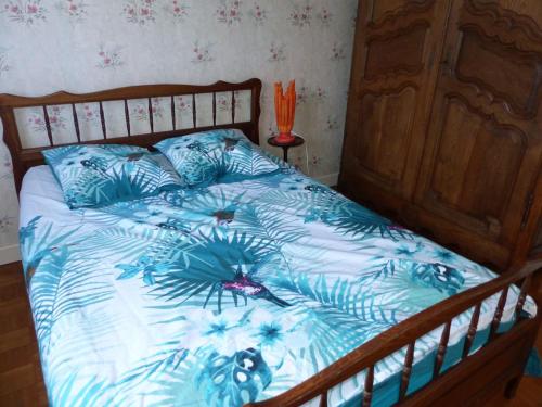 a bed with a blue comforter with ailantro at Chez Karinette in Les Rivières-Henruel