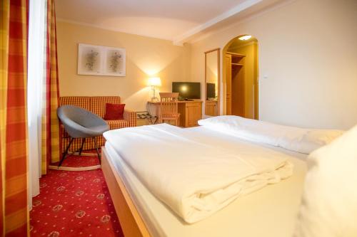 ein Hotelzimmer mit einem Bett und einem Stuhl in der Unterkunft Wirtshaus Restaurant Pension Steirerland in Mureck
