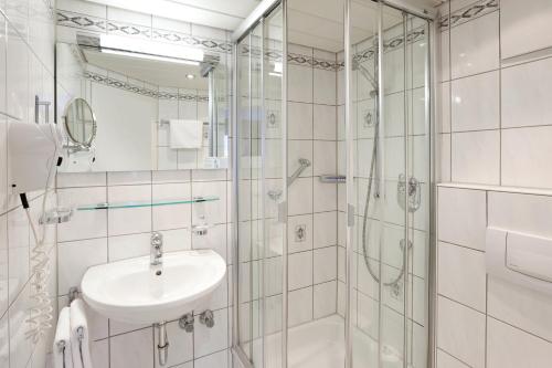 uma casa de banho branca com um lavatório e um chuveiro em Hotel garni Kappeler-Haus em Oberstdorf