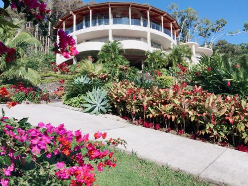a flower garden in front of a house at Villa Maria in Rarotonga
