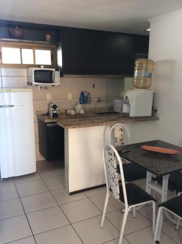 uma cozinha com um frigorífico branco e uma mesa com cadeiras em Atlantic Ocean Residence Sea em Fortaleza