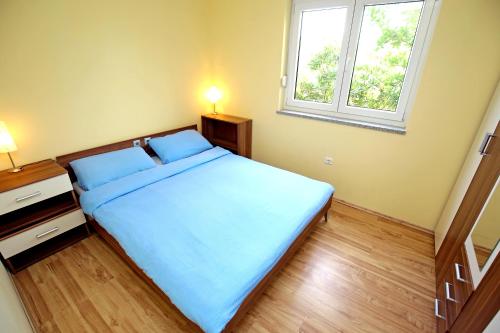 a bedroom with a bed with blue sheets and a window at SOLARIS ANTONELA Modern Apartments with Sea View & Free Private Parking in Sveti Filip i Jakov