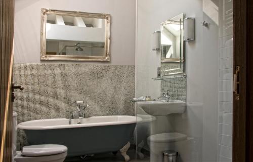 a bathroom with a tub and a sink and a mirror at The Swallows Rest Bed & Breakfast in Brigstock